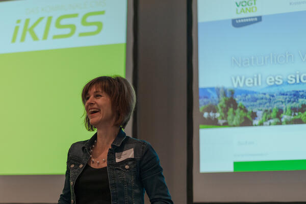 Projektleiterin Beate Grohs berichtet begeistert vom neuen Internetauftritt des Vogtlandkreises, der im Hintergrund auf einer Leinwand zu sehen ist